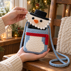 Hands hold an icy-blue snowman phone bag with its bobble-edged flap lifted and a phone peeking from the opening, beside a wooden chair.