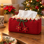 Red crochet tissue box cover with cream lace, a green bow and two red pointed poinsettias beside a lamp and potted poinsettia.